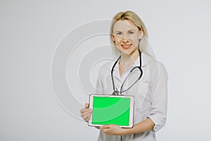 Smiling female doctor with stethoscope showing blank digital tablet pc.