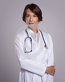 Smiling female doctor with stethoscope standing at isolated background