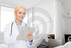 smiling female doctor with tablet pc in hospital