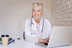 Smiling female doctor working on laptop at the doctor`s office