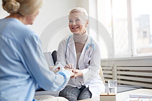 Smiling Female Dostor Holding Hands with Patient photo