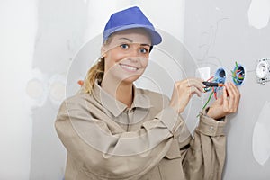 smiling female electrician installing wall socket