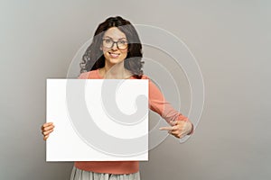 Smiling female with empty poster point to blank placard, show advertisement on billboard or banner