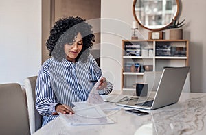 Smiling female entrepreneur going through paperwork at her dining table