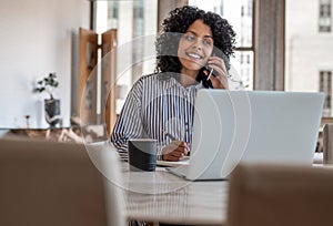 Smiling female entrepreneur sitting at home talking on her cellphone