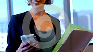 Smiling female executive using mobile phone in office