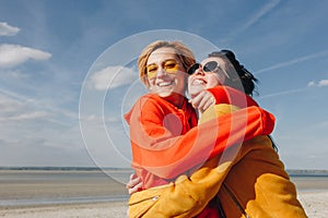 smiling female friends embracing on sandy beach Saint michaels mount