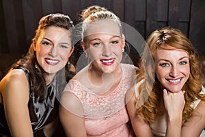 Smiling female friends sitting together in sofa at bar