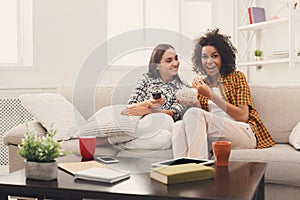 Smiling female friends watching TV at home