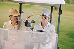 smiling female golf players riding golf cart