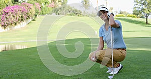 Smiling female golfer with brown hair crouches