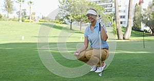 Smiling female golfer with brown hair crouches