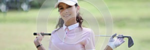 Smiling female golfer holding golf club closeup