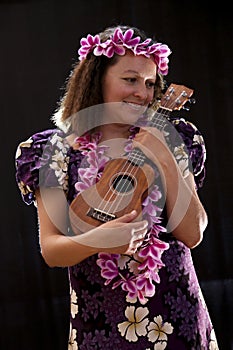 Smiling female Hawaiian girl dancing and singing with musical instruments like the ukulele