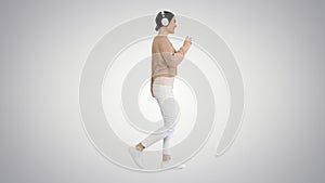 Smiling female with headphones walking and dancing to the music
