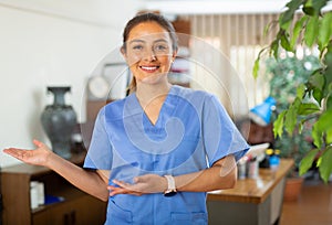 Smiling female health worker in blue uniform welcoming to medical office