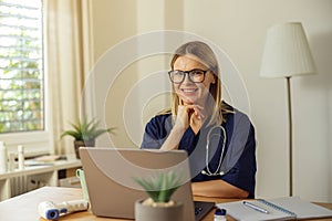 Smiling female healthcare worker using laptop while working at doctor& x27;s office. Healthcare concept