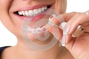 Smiling female holding invisible teeth braces