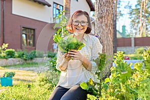 Smiling female holding set of popular culinary herbs arugula dill lettuce leaves