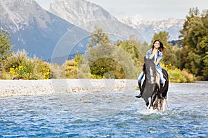 Smiling Female horse rider crossing river