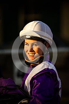 Smiling female jockey with a dark background