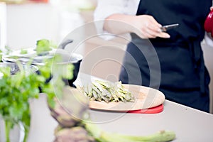 Smiling female kitchener in uniform is standing in the kitchen at the restaurant