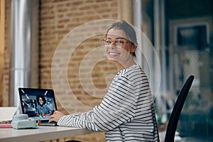 Smiling female manager talking via video call with colleague during meeting in office