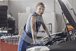 Smiling female mechanic working at the auto repair shop