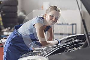 Smiling female mechanic working at the auto repair shop