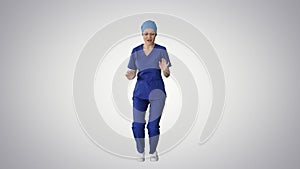 Smiling female medical doctor in blue uniform dancing and cheering on gradient background.