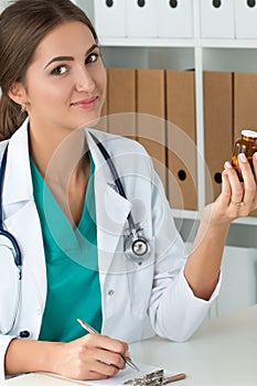 Smiling female medicine doctor holding bottle with pills