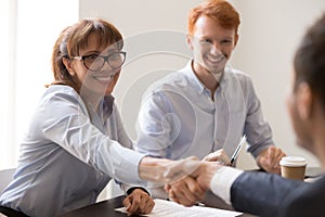 Smiling female middle aged hr manager handshaking hiring male applicant