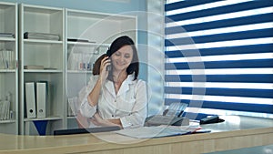 Smiling female nurse answering phone call at the reception desk