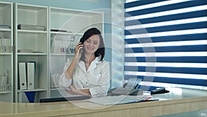 Smiling female nurse answering phone call at the reception desk
