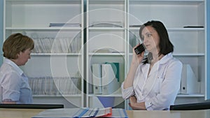 Smiling female nurse answering phone at the hospital reception desk