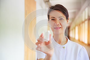 Smiling female nurse holding pill cup in her hand for patients. Professional, Specialist, Nurse, Doctor in white uniform concept