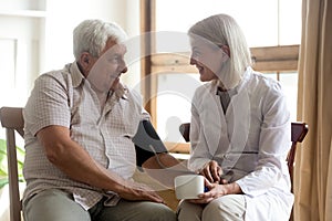 Smiling female nurse measure blood pressure of senior male patient