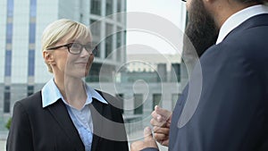 Smiling female office worker listening to boss outside building, private chat