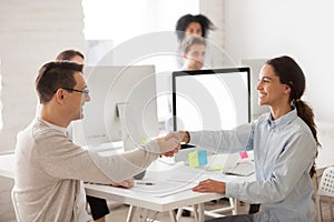 Smiling female worker congratulating job applicant with successf photo