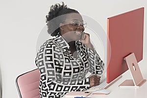 A smiling female office worker sitting at desk with desktop computer.