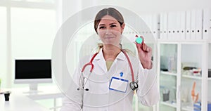 Smiling female ophthalmologist holding contact lenses and glasses