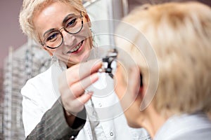 Smiling female optometrist examining mature woman, determining diopter in ophthalmology clinic