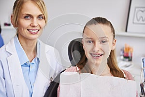 Smiling female orthodontist and child in dentist`s office photo