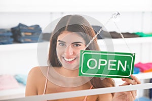 Smiling Female Owner Holding Open Sign In Clothing Store