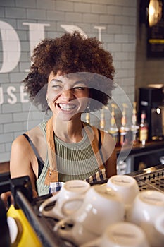 Smiling Female Owner Or Staff Serving Behind Counter In Coffee Shop