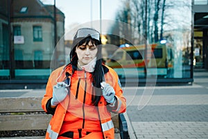 Smiling female paramedic with lowered respirator looks at you