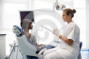 Smiling female patient having consultation at dentist office