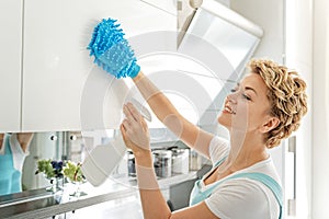 Smiling female person cleaning cupboard