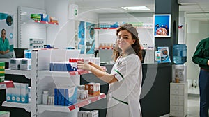 Smiling female pharmacist examining packages of pills to help clients