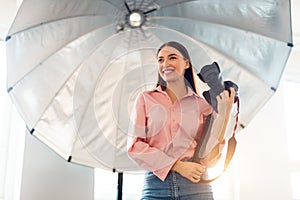 Smiling female photographer with camera in studio